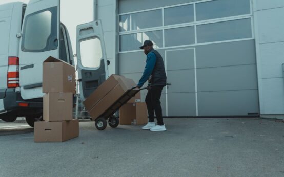 Courier unloading packages from a delivery van at a warehouse entrance. Efficient distribution.