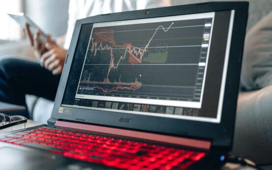 Close-up of a laptop displaying stock charts with a person in background.